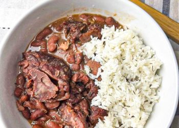 Slow Cooker Red Beans served in a white bowl garnished with fresh herbs and a side of rice, illustrating the final delicious meal made from the recipe.