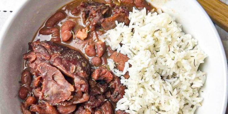 Slow Cooker Red Beans served in a white bowl garnished with fresh herbs and a side of rice, illustrating the final delicious meal made from the recipe.