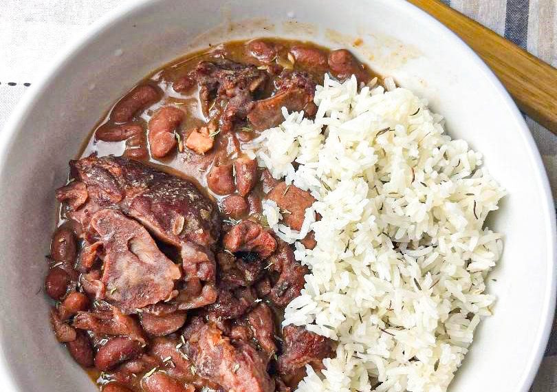 Slow Cooker Red Beans served in a white bowl garnished with fresh herbs and a side of rice, illustrating the final delicious meal made from the recipe.