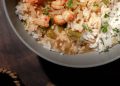 Bowl of steaming étouffée with shrimp and crawfish over white rice, garnished with green onions