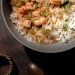 Bowl of steaming étouffée with shrimp and crawfish over white rice, garnished with green onions